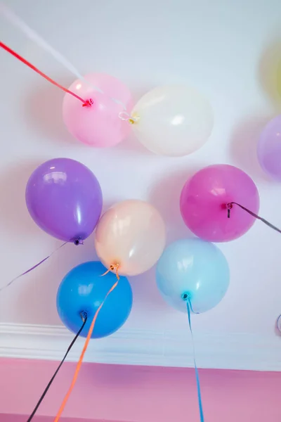 Bunte Luftballons schweben an der weißen Decke im Partyraum. Hochzeit oder Kindergeburtstag Dekoration Innenraum. Heliumballons . — Stockfoto