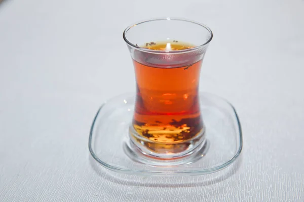 Thé en verre traditionnel armudu azerbaïdjanais en forme de poire. Thé noir Azerbaïdjan avec table blanche vintage. Thé turc noir en verre en forme de poire, thé aromatique azerbaïdjanais traditionnel en tasse armudu  . — Photo