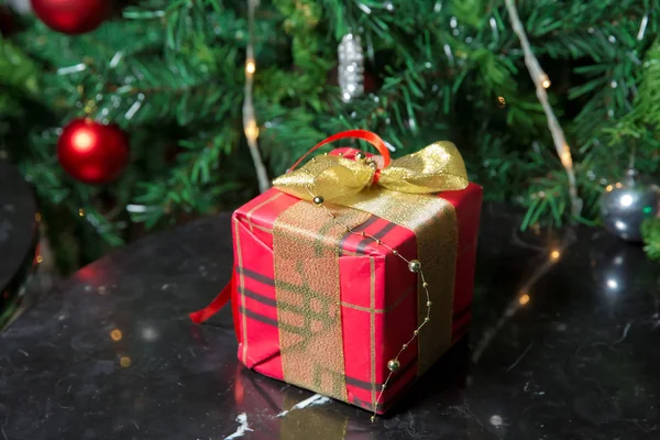 Presentes sob a árvore de Natal decorados com fita golg e arco. Um presente de Natal vermelho. Bela árvore de Natal com bolas vermelhas . — Fotografia de Stock