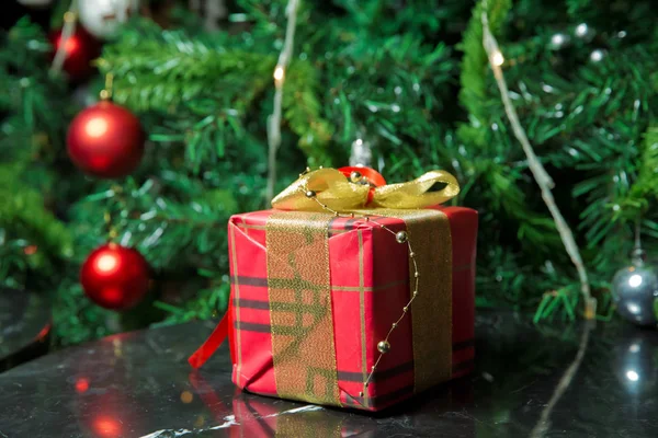 Presentes sob a árvore de Natal decorados com fita golg e arco. Um presente de Natal vermelho. Bela árvore de Natal com bolas vermelhas . — Fotografia de Stock