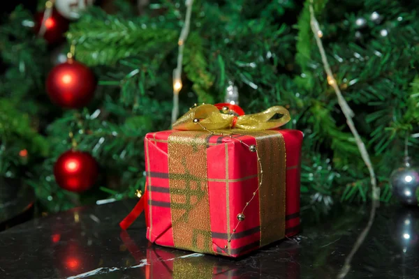 Presentes sob a árvore de Natal decorados com fita golg e arco. Um presente de Natal vermelho. Bela árvore de Natal com bolas vermelhas . — Fotografia de Stock