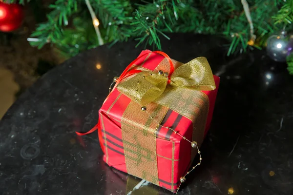 Presentes sob a árvore de Natal decorados com fita golg e arco. Um presente de Natal vermelho. Bela árvore de Natal com bolas vermelhas . — Fotografia de Stock