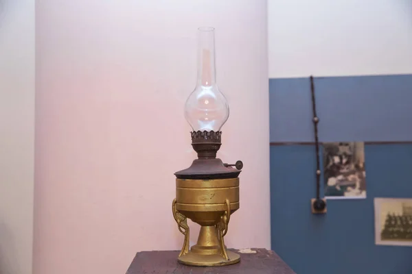 Vintage kerosene lamp on wooden table .vintage kerosene oil lantern lamp burning with a soft glow light in an antique rustic country barn with aged wood floor . Kerosene lamp on rustic wooden table.