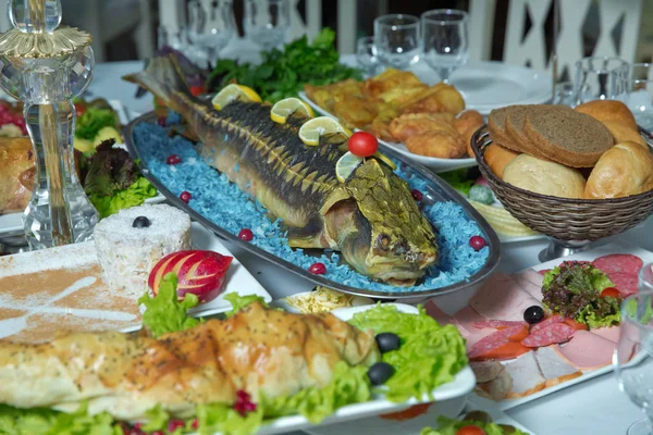 Cooked fish is on the table .Grilled sturgeon fish. Grilled sturgeon fish. Healthy food.bread, sausage, salad. Sturgeon baked with vegetables. Healthy food. grilled fish .