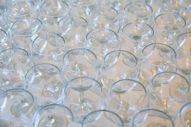 Şampanya ve şarap için barmen tarafından hazırlanan bir masada üst üste duran boş temiz bardaklar. Rafta birkaç şeffaf gözlük var. Etkinlik için catering. Arka arkaya bir sürü şarap kadehi .