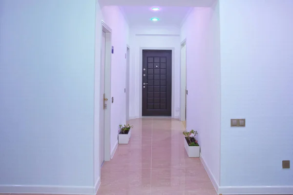 Foto quadrata di lungo corridoio di casa con porte e armadio. luce rosa .Door modo spazio interior lighting design. Pareti bianche e porta in corridoio con pavimento in legno  . — Foto Stock