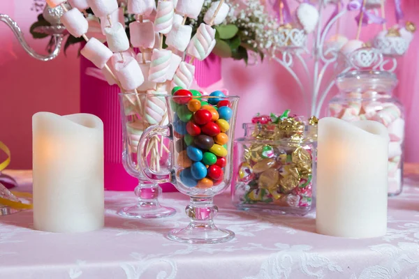 Барвисті цукерки. Багатокольорові цукерки. Кольорові цукерки в склянці. Круглий шоколад дуже барвистий. Свічка  . — стокове фото