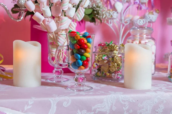 Красочные конфеты. Разноцветные конфеты. Цветные конфеты в стакане. Круглый шоколад очень красочный. Свеча  . — стоковое фото