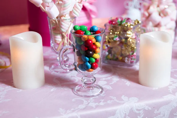 Bunte Bonbons. Bunte Süßigkeiten. farbige Bonbons im Glas. runde Schokolade ist sehr farbenfroh. Kerze . — Stockfoto