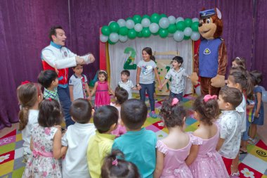 Anaokulunda iki yıl doğum günü. Animatörlerle çocukların doğum günü. Mutlu bir grup çocuk doğum günü kutlamasında bir animatörle pati devriyesi tarzında giyinmişler. .