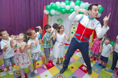 Anaokulunda iki yıl doğum günü. Animatörlerle çocukların doğum günü. Mutlu bir grup çocuk doğum günü kutlamasında bir animatörle pati devriyesi tarzında giyinmişler. .