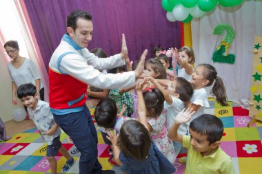Anaokulunda iki yıl doğum günü. Animatörlerle çocukların doğum günü. Mutlu bir grup çocuk doğum günü kutlamasında bir animatörle pati devriyesi tarzında giyinmişler. .