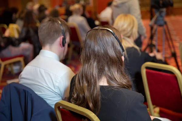 Unrecognizable business people using headphones for translation during event . bald security guard with the headset to control people . heated debate at a conference discussion