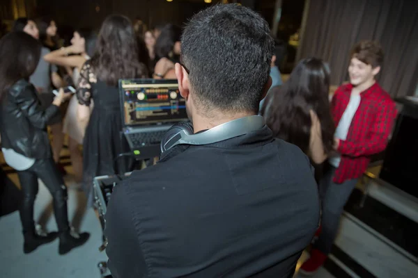 DJ met koptelefoon op nachtclub feest onder het kleurrijke licht en mensen menigte op de achtergrond. DJ op een open aire party. Nachtfeest aan zeekust. — Stockfoto