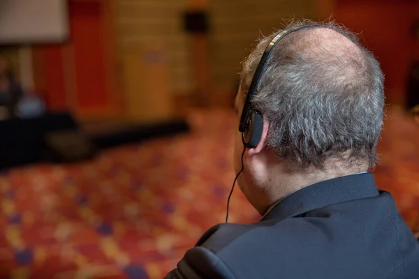 Geschäftsleute, die während der Veranstaltung über Kopfhörer übersetzen, sind nicht wiederzuerkennen. Glatzköpfiger Sicherheitsmann mit Headset zur Personenkontrolle. Hitzige Debatte auf einer Konferenz — Stockfoto