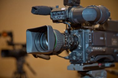 Mükemmel kırpma yolu olan bir tripoda yerleştirilmiş profesyonel video kamera. Profesyonel prodüksiyon kamerası. İş konferans odasındaki video kamera katılımcıları kaydediyor
