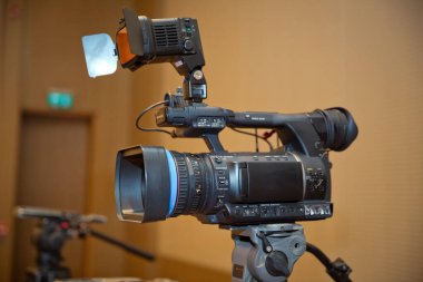 Mükemmel kırpma yolu olan bir tripoda yerleştirilmiş profesyonel video kamera. Profesyonel prodüksiyon kamerası. İş konferans odasındaki video kamera katılımcıları kaydediyor