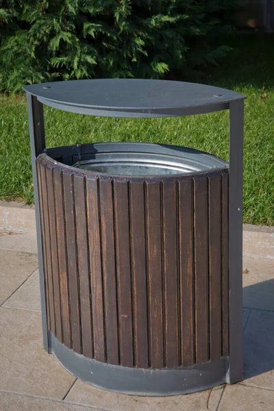 Cubo de basura negro dentro de un recinto de madera en un parque. espacio de copia a la izquierda. Caja de basura en el parque  . —  Fotos de Stock