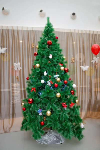 Christmas tree with red decorations, gift box in white background, Christmas concept interior room . Joyful studio shot of a Christmas tree with colorful ornaments . — Stock Photo, Image