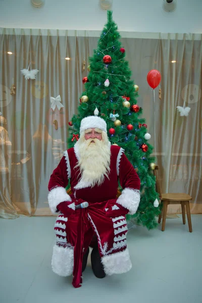 Pai Natal contra casa com árvore de Natal. Papai Noel carrega um pouco de Natal contra casa com árvore de Natal. O rosto de Santana é branco. Em vez de colocar a cabeça na cara em vez de fotografar — Fotografia de Stock