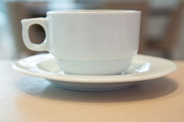 Beyaz fincan, beyaz soslu kahve. Kafe bulanık arka planda bir fincan sıcak kahve. Beyaz porselen fincanda kahve çekirdekleri ve yabani otlar. .