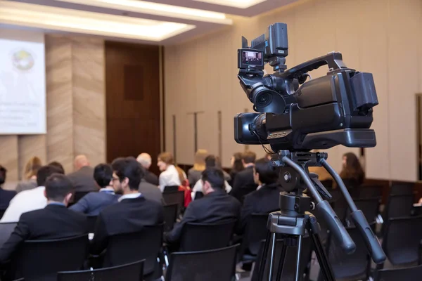 Shooting the film scene with camera in film studiocamera in a concert or conference hall.Video cameras operator working with his equipment. Selective focus . Behind the scene.