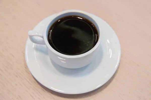 Weiße Tasse, Kaffee in weißer Sauce.Tasse heißen Kaffee auf dem Tisch im Café verschwimmen Hintergrund. Kaffeebohnen in weißer Porzellantasse mit Wildkräutern dekoriert . — Stockfoto