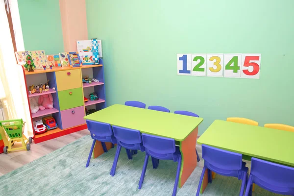 Kids . Children's playroom with plastic colorful educational blocks toys . Shelf with many colored toys . Children sit at tables in the garden . Baby's room with shelves with toys .