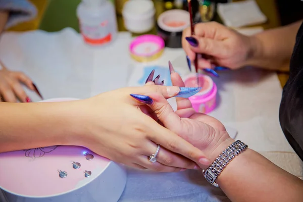 Mujer en un salón de uñas recibiendo una manicura por una esteticista. Proceso de manicura en hermoso salón. Primer plano de la mujer aplicando barniz de uñas a las uñas de los dedos. Salón de manicura manos  . — Foto de Stock