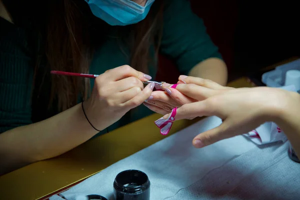 Manicure hands salon . Woman in a nail salon receiving a manicure by a beautician . Manicure process in beautiful salon . Closeup of Woman applying nail varnish to finger nails
