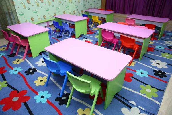 Sandalyesi ve masası olmayan çocuklar için bir okulun yemekhanesi. İçinde küçük çocuklar için masa ve sandalyeler olan geniş bir anaokulu odası..