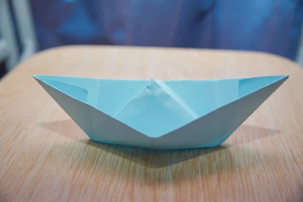 Origami paper ship . Leadership concept with blue paper ship leading among wooden . Blue paper boat on wooden background .