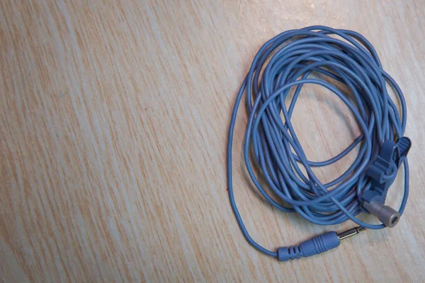 Blue Microphone and headphone splitter cable . Audio Mini Jack Cable for microphone isolated on wooden background .