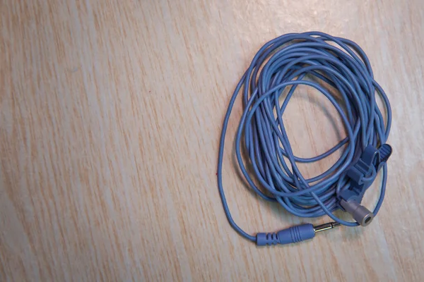 Blue Microphone and headphone splitter cable . Audio Mini Jack Cable for microphone isolated on wooden background .