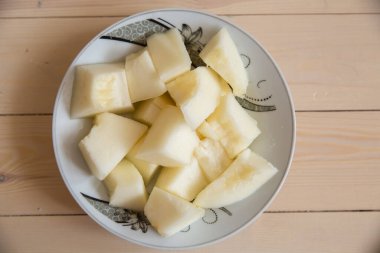 Dilimlenmiş beyaz bir tabakta ahşap bir arka planda. Ahşap kaplamalı karpuz dilimi .