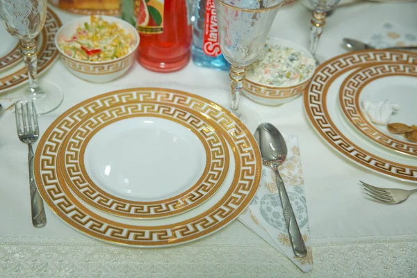 Пустая тарелка, золотой набор на деревянном белом столе. Красиво украшенный стол с золотыми пластинами, льняная салфетка, ложка, вилка . — стоковое фото