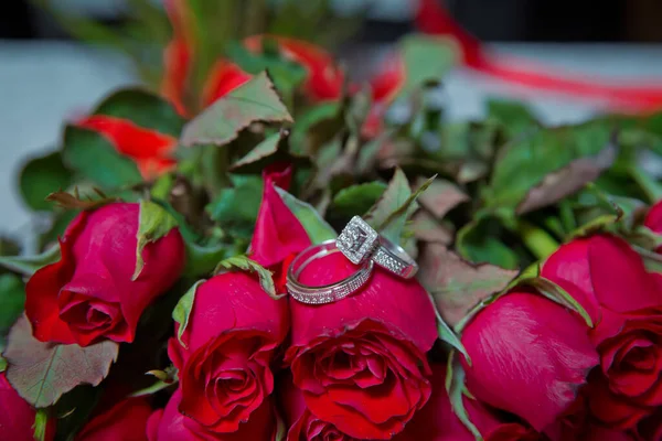 Düğün buketindeki yüzükler. Bir buket kırmızı çiçekte altın alyanslar.. — Stok fotoğraf