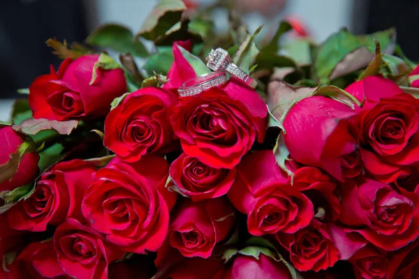 Ringen op het bruiloft boeket. Gouden trouwringen op een boeket van roodgouden bloemen. — Stockfoto