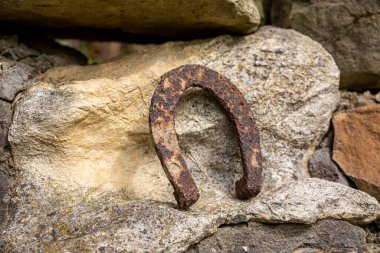 Büyük bir taşın üzerinde duran paslı bir at nalının yakın çekimi..