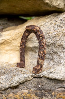 Büyük bir taşın üzerinde duran paslı bir at nalının yakın çekimi..