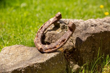 Büyük bir taşın üzerinde duran paslı bir at nalının yakın çekimi..