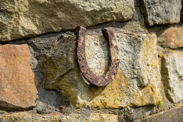 Primer plano de una vieja herradura oxidada apoyada en una gran piedra. —  Fotos de Stock