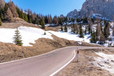 Bahar Dolomites içinde asfalt yol. Dağlar ve ormanlar mavi gökyüzü karşı.