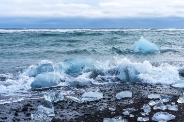 Jokulsarlon gölü yakınlarında buzdağı parçaları bulunan siyah kumsal manzarası inanılmaz. Kış zamanı İzlanda..