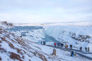 GLLFOSS, ICELAND - 4 Mart 2020: İzlanda 'nın en popüler turistik merkezlerinden biri olan Gullfoss Şelalesi' ne bakan insanlar. İzleme güvertesindeki turistler İzlanda 'daki Gullfoss şelalesine bakıyorlar..