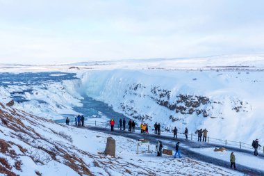GLLFOSS, ICELAND - 4 Mart 2020: İzlanda 'nın en popüler turistik merkezlerinden biri olan Gullfoss Şelalesi' ne bakan insanlar. İzleme güvertesindeki turistler İzlanda 'daki Gullfoss şelalesine bakıyorlar..