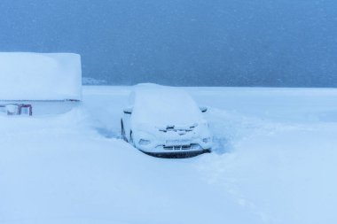 Şiddetli kar yağışı ve karla kaplı bir araba.