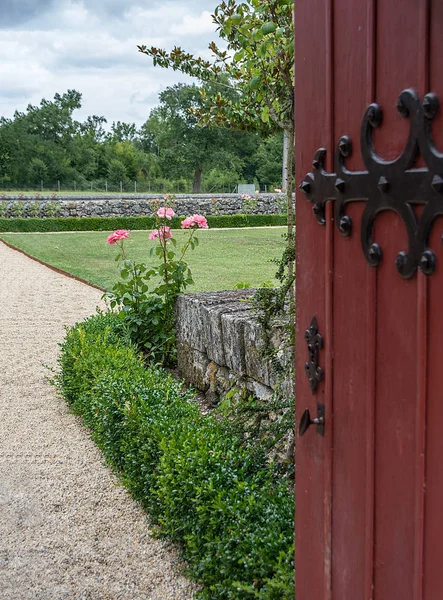 An open gate invites you to the garden with roses