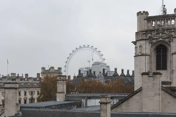 ЛОНДОН, ОБЪЕДИНЕННЫЙ КИНГДОМ - 24 НОЯБРЯ 2018 года: London Eye behind the old vintage historic traditional style buildings roofs — стоковое фото