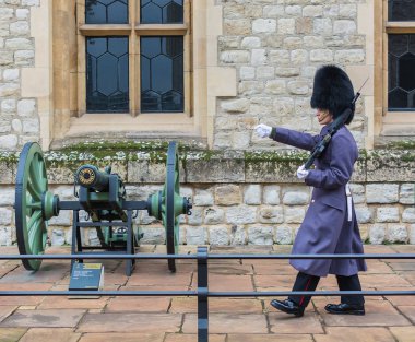 Tower of London, London, Büyük Britanya - 24 Kasım 2018: Kraliyet muhafızı. Genç asker yürüyüşleri yakınındaki bir silah